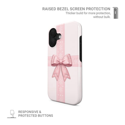 Glossy tough phone case with blush ribbon and large pink bow with white snowflakes on a soft pastel background, Case & Charm Winter’s Gift design